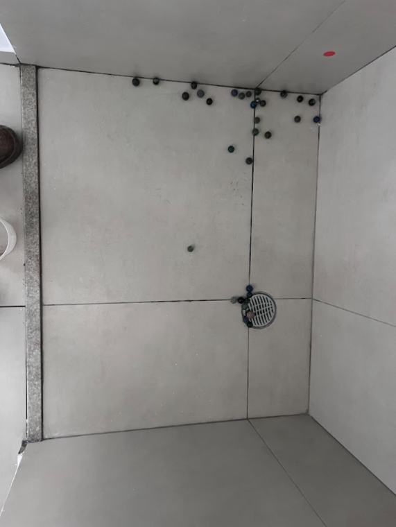 Box de banheiro com marcações de teste de som cavo no revestimento cerâmico