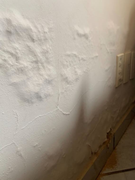 Parede com umidade, bolhas de pintura e descolamento de reboco junto ao rodapé